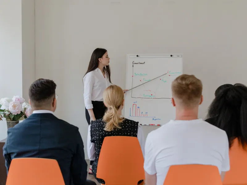 Facilitadora impartiendo una clase presencial frente a un grupo de colaboradores